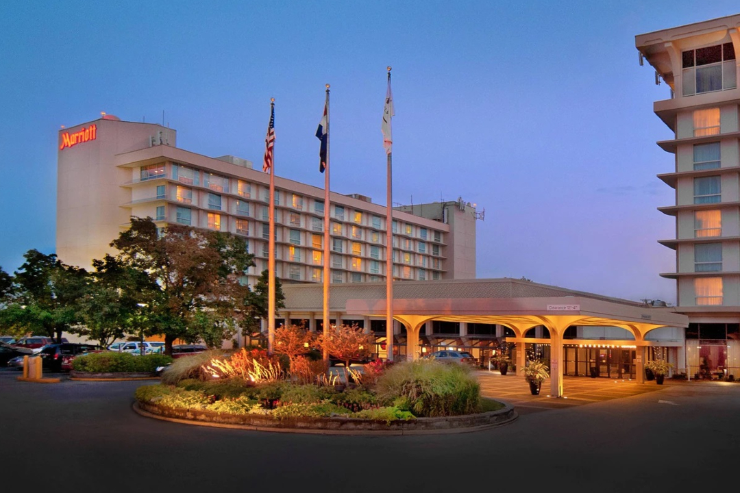 Exterior shot of the Marriott St. Louis Airport hotel at dusk, with lights casting a warm glow on the guest entrance